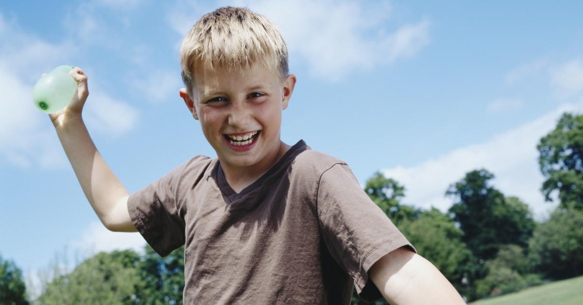 A blonde-haired boy getting ready to throw a water balloon.