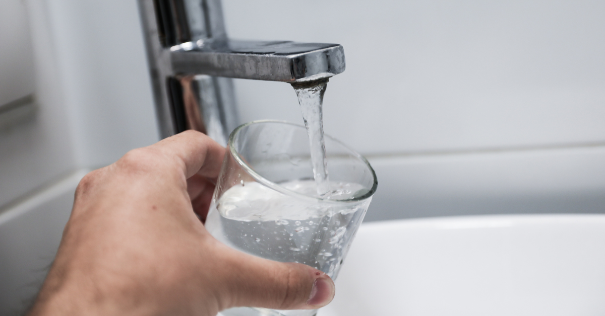 Water pouring out of a tap and into a drinking glass