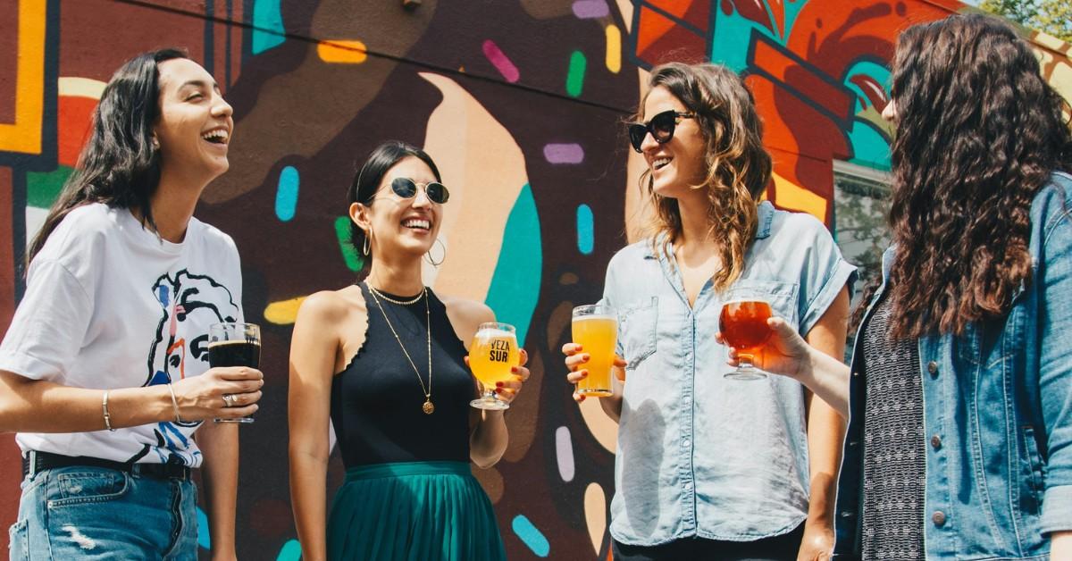 A bunch of young adults stand around with drinks