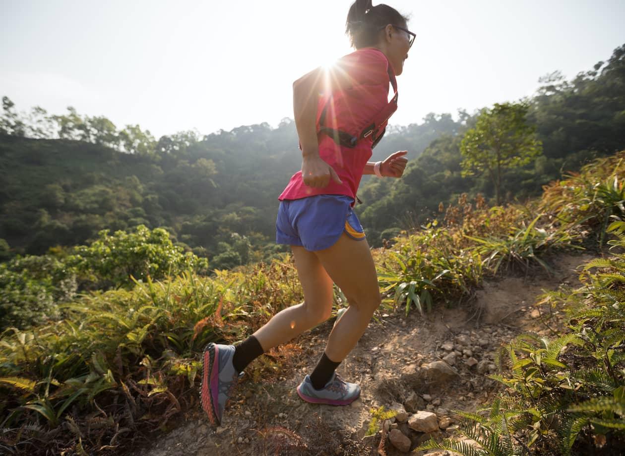 Woman trail runner running up a mountain slope in a tropical forest