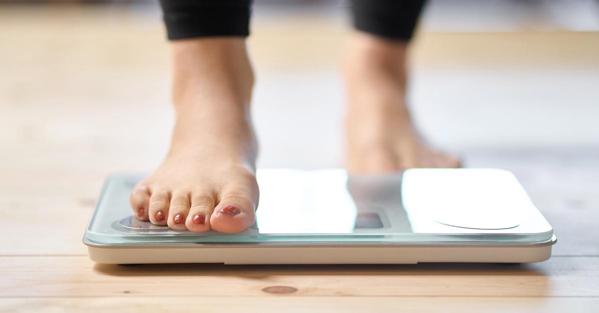 Person trying to lose weight standing on a scale.