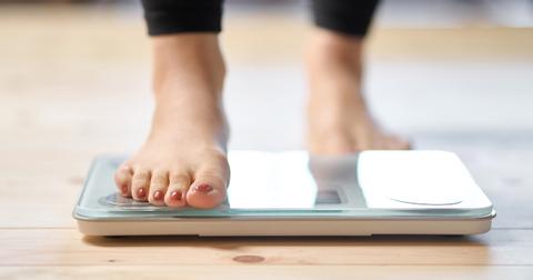 Person trying to lose weight standing on a scale.