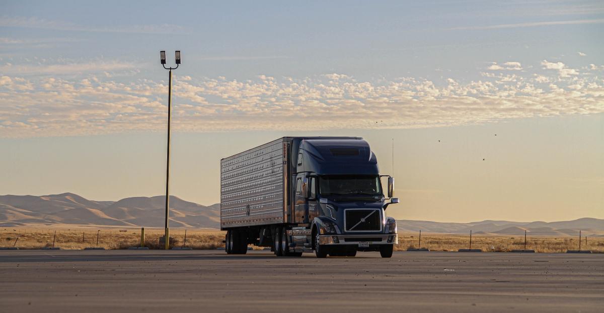 Semi-truck in parking lot by mountains and desert.