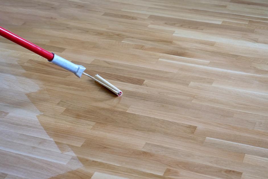 A roller moves across light hardwood floors to polish the surface. 