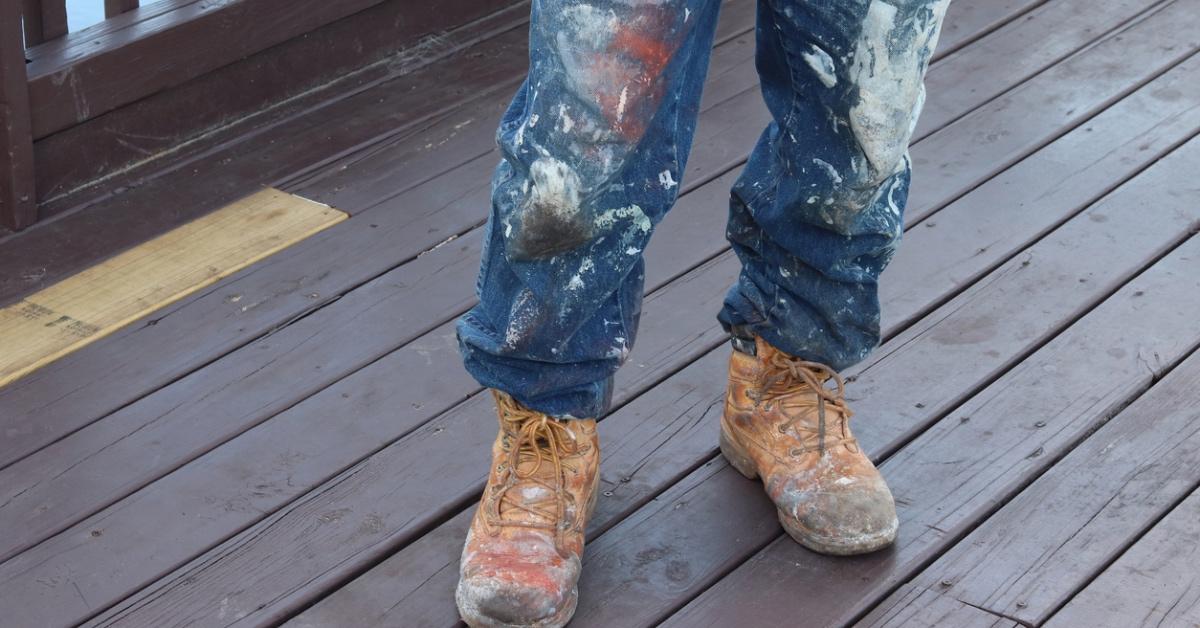 Person with paint on their jeans standing on a wooden deck. 