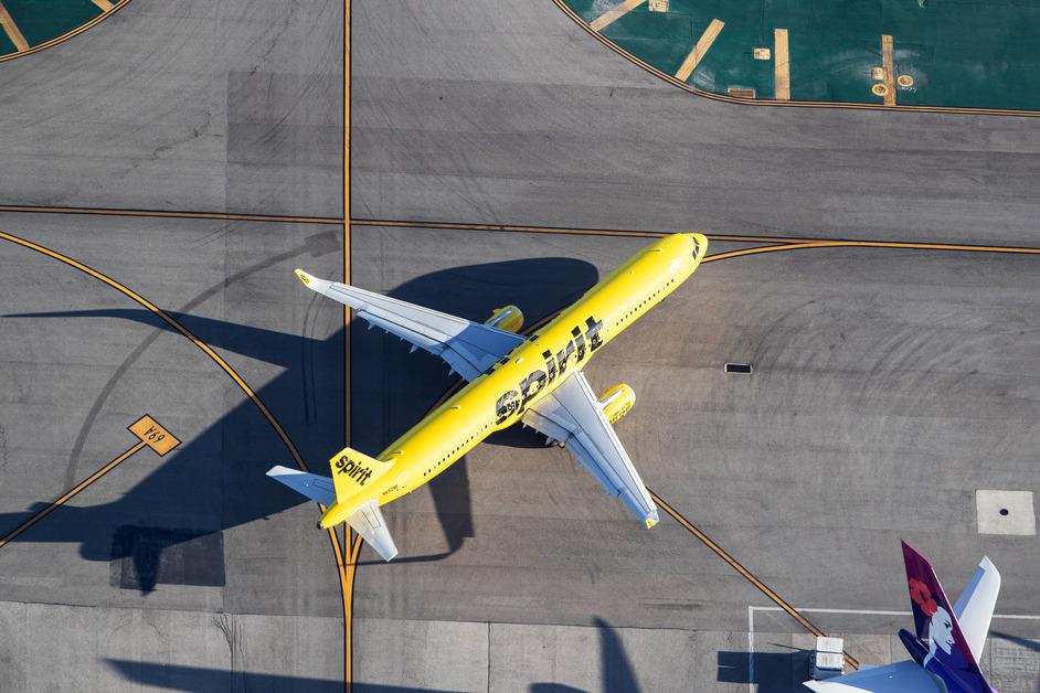 An aerial view of a yellow Spirit Airlines plane on an airport runway. 