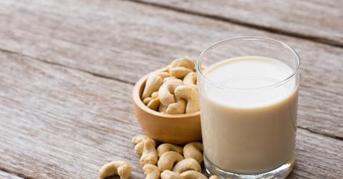 Cashews in a bowl next to cashew milk.