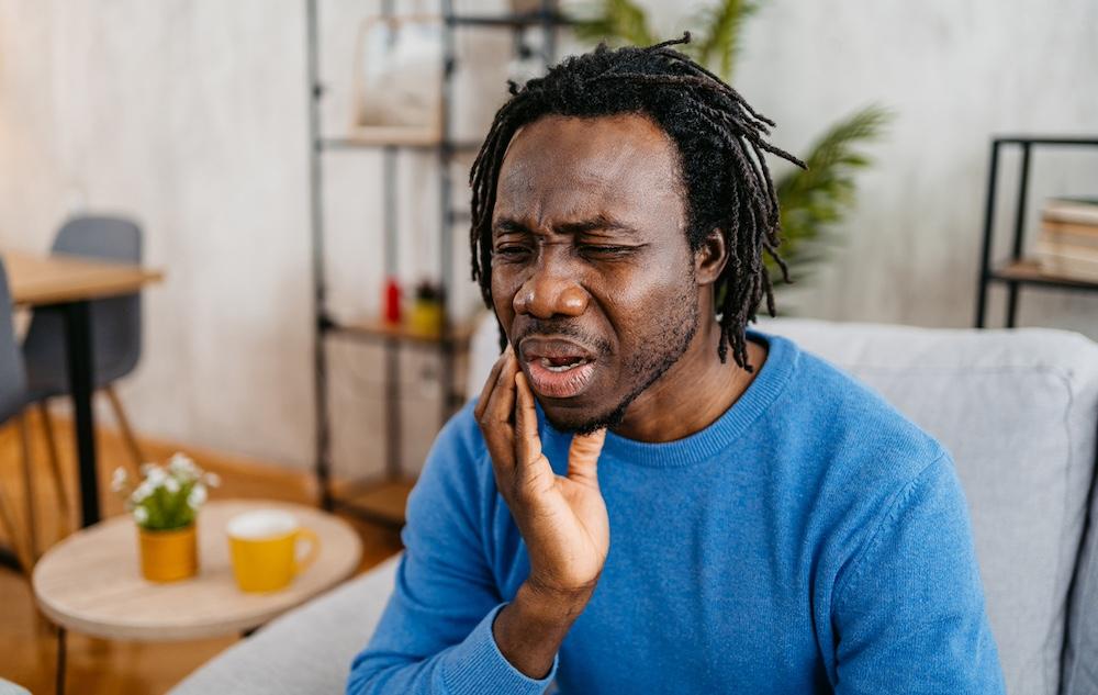 A man sitting a home in his living room with a toothache.