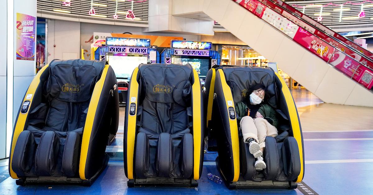 Woman wearing face mask in massage chair in mall