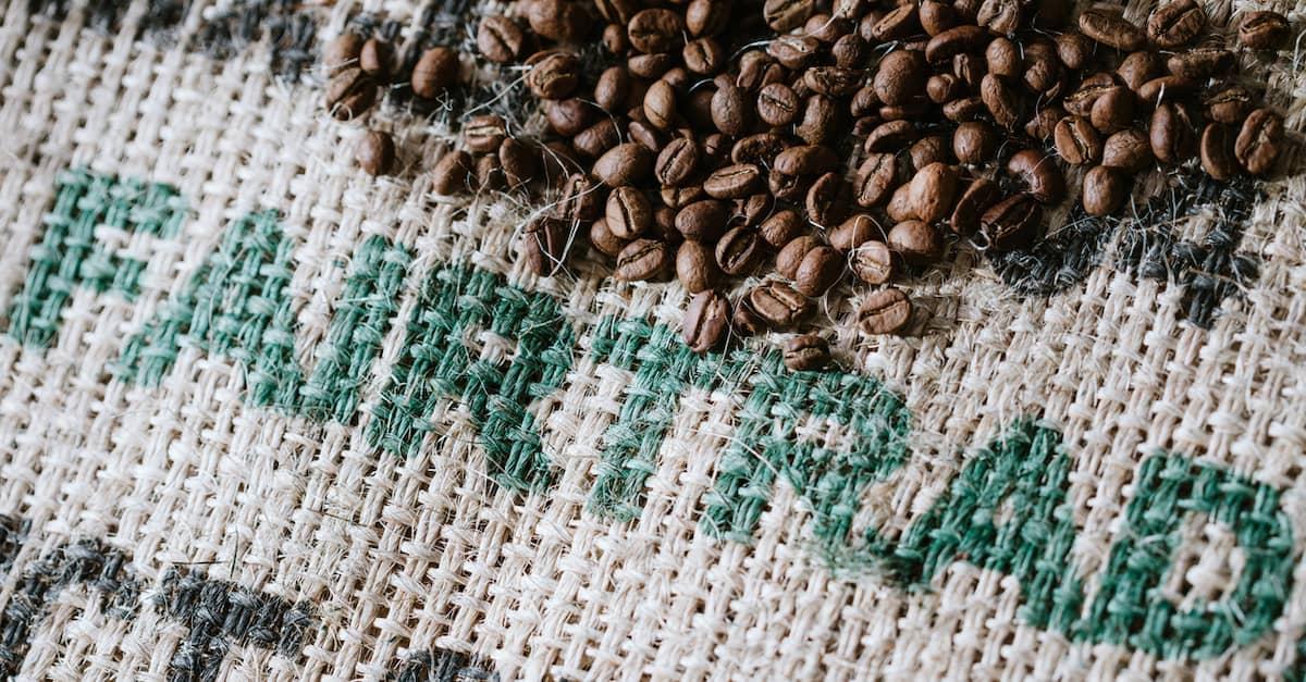 Closeup of coffee beans on a burlap sack with the word fairtrade stamped on it