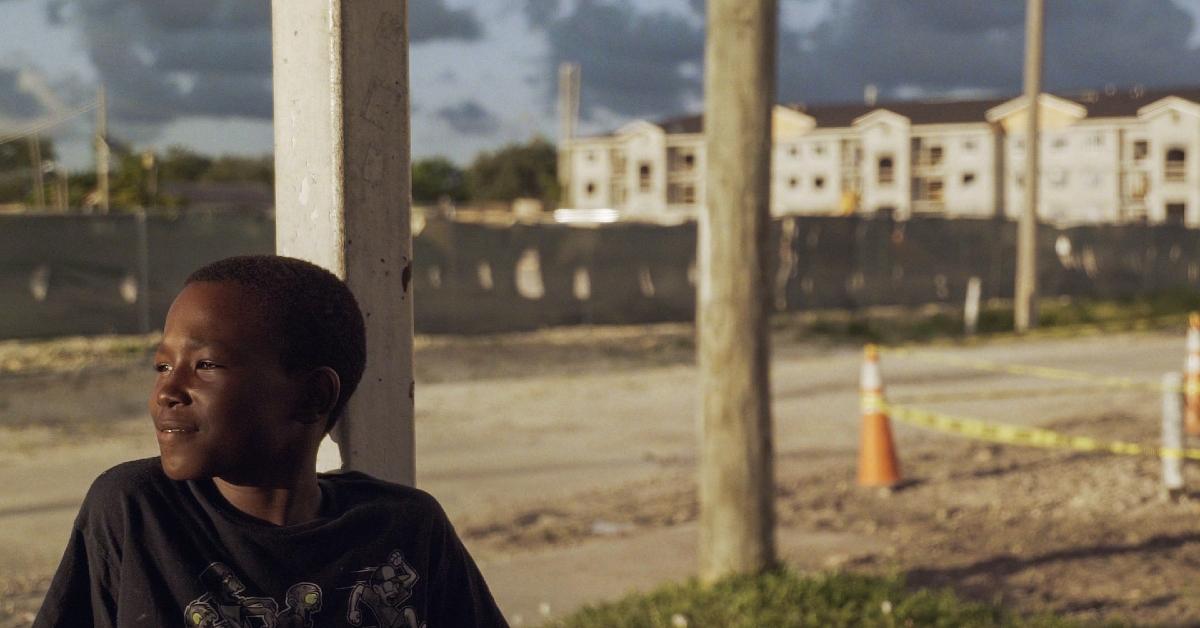 Photo of young boy sitting on back porch in Miami's Liberty Square neighborhood