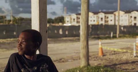 Photo of young boy sitting on back porch in Miami's Liberty Square neighborhood