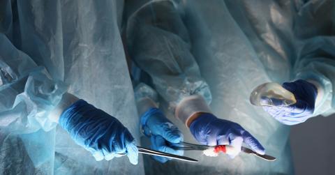 Hands in medical globes hold surgery tools