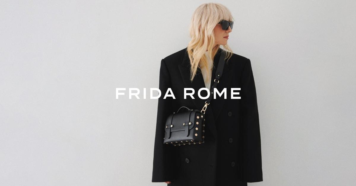 Sara Luxe, a blonde model, wears a black jacket and black Frida Rome handbag, with the text "Frida Rome" in white in the center of the photo.