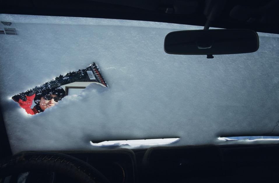 Woman clearing snow off windshield