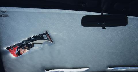 Woman clearing snow off windshield