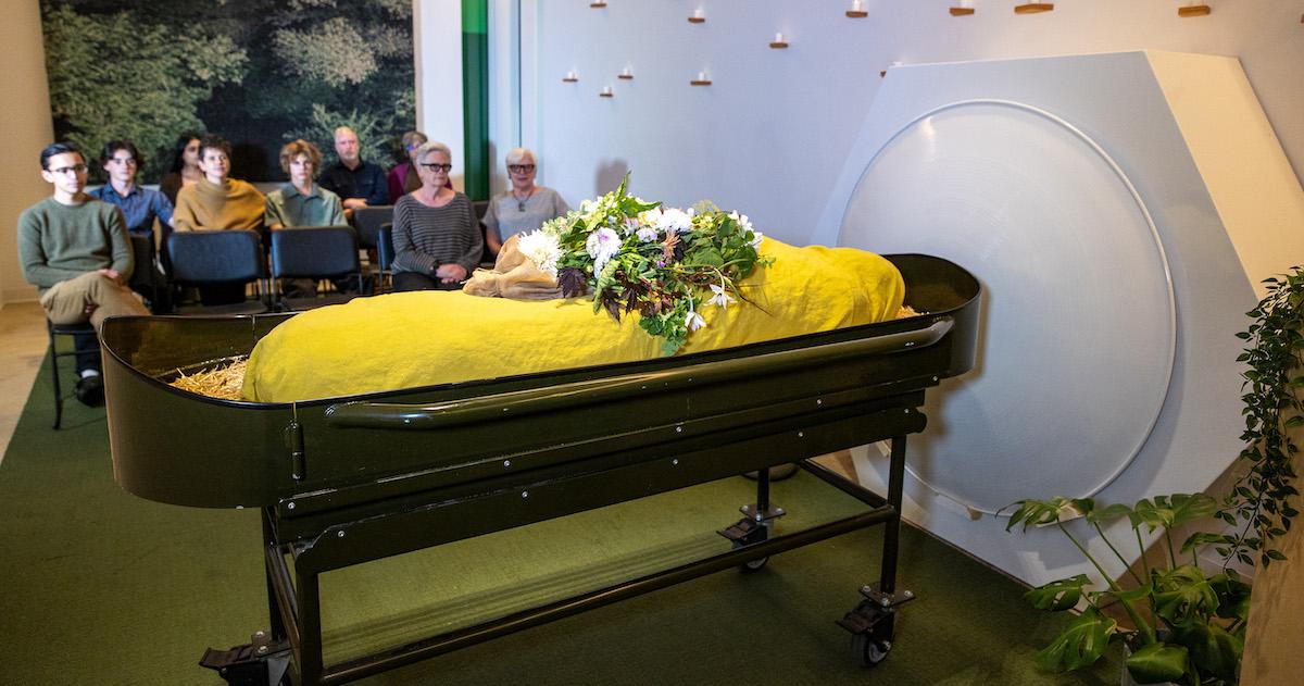 Guests sit in the gathering space looking at a shrouded mannequin in front of the threshold vessel at Recompose, a green funeral home specializing in human composting, also known as natural organic reduction, terramation, or recomposition at Recompose Seattle on Oct. 6, 2022 in Seattle.