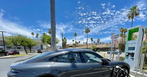 black EV Porsche at charging station with palm trees surrounding