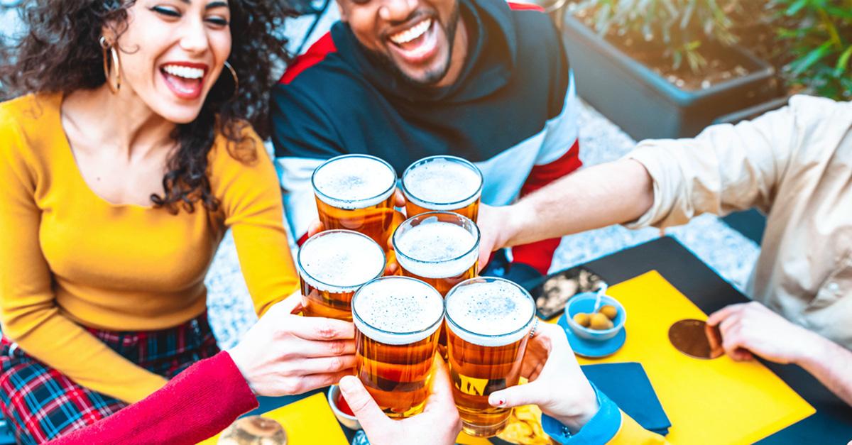 women and men toasting with glasses of beer at a gathering