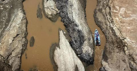 A small boat passes through a drought-hit region of the Amazon River (Cover Image Source: Getty Images | Bruno Zanardo)