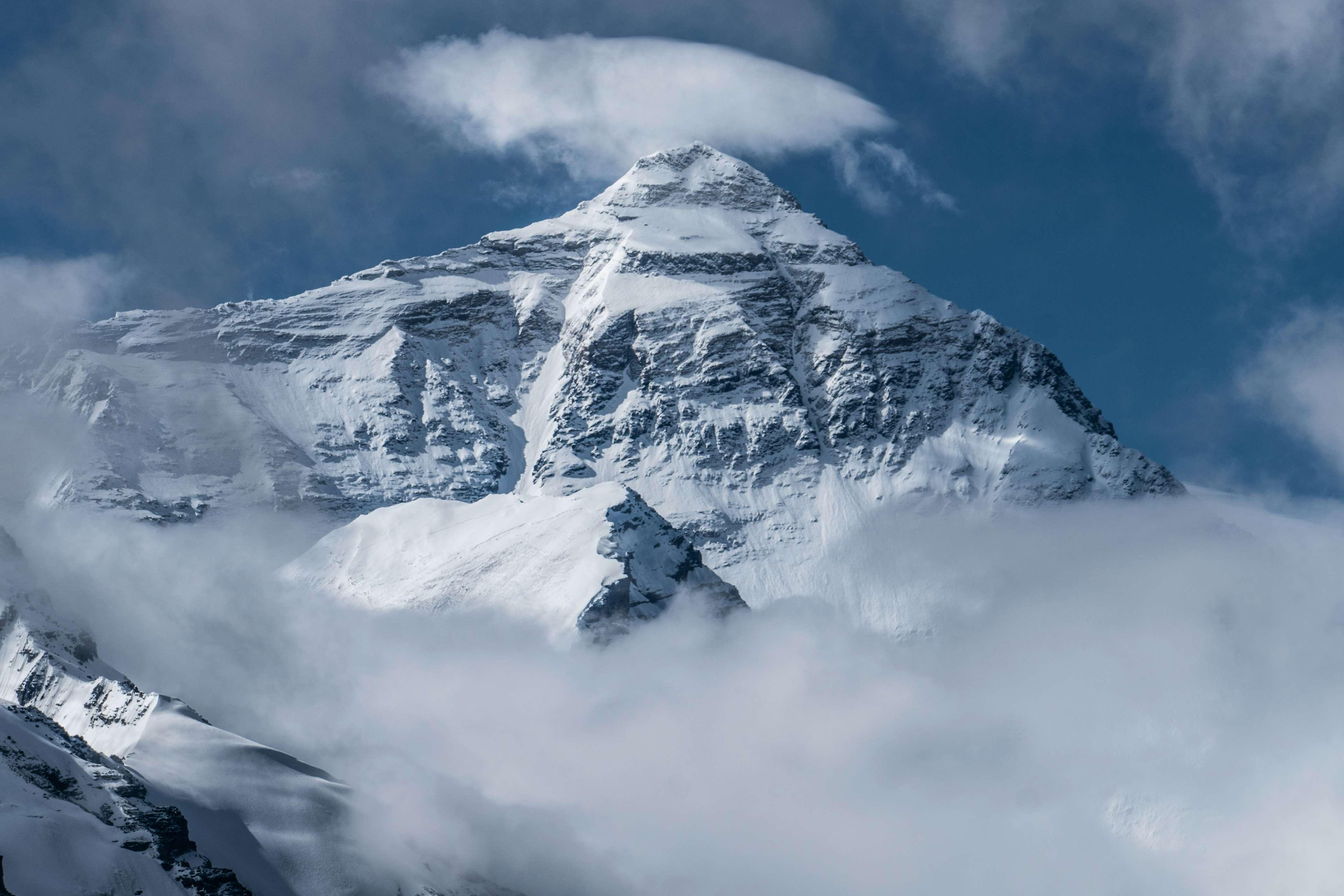 Mount Everest is pictured with snow on the mountain and clouds surrounding it.