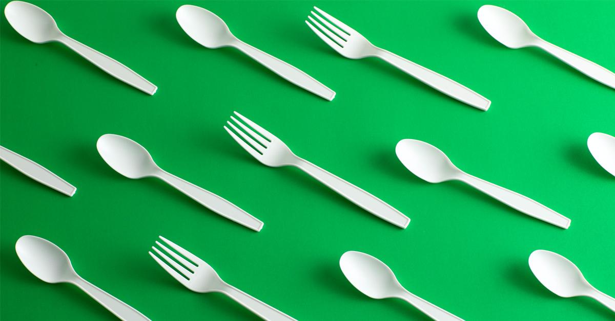 disposable forks and spoons on a green background