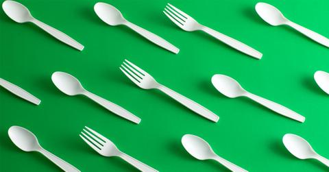 disposable forks and spoons on a green background