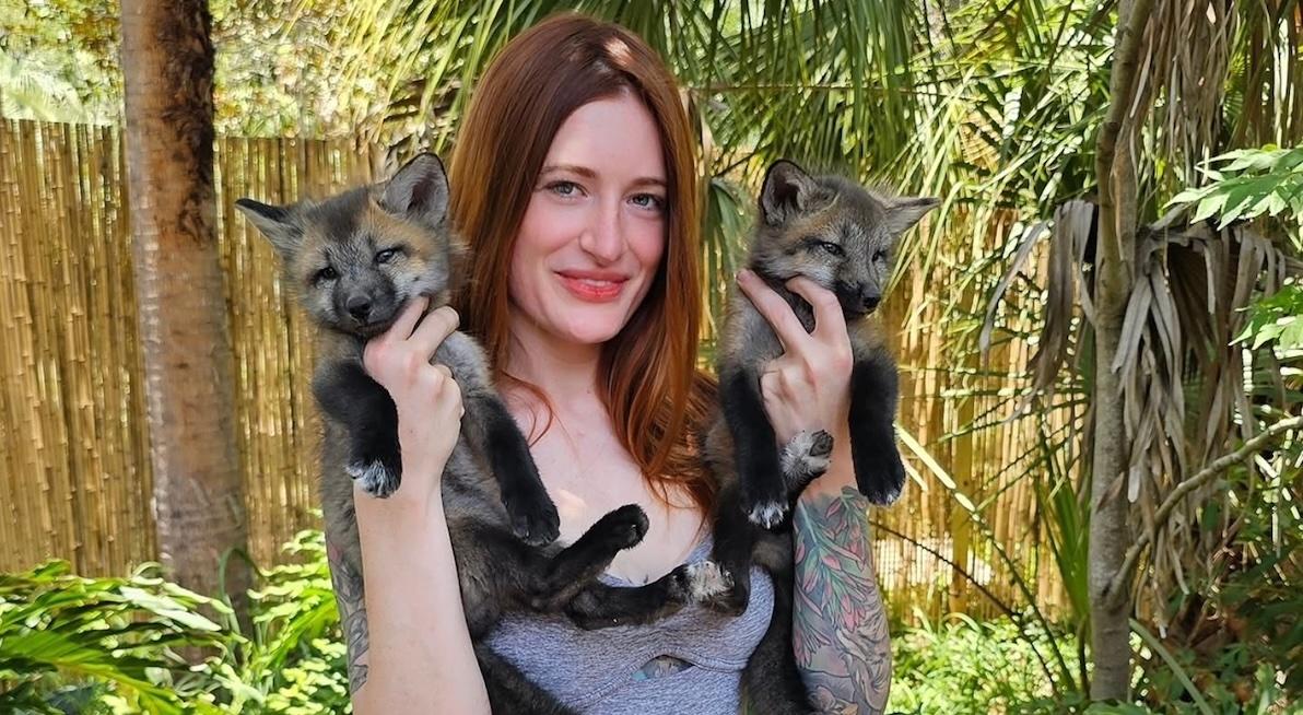 mikayla raines holding two baby foxes