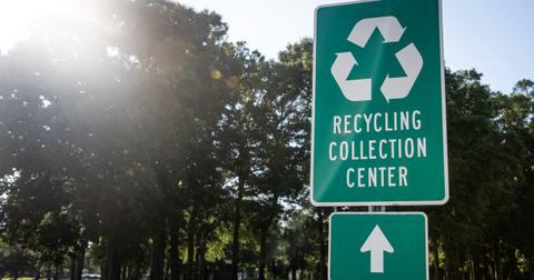 A green sign outside that reads "recycling collection center" and has an arrow indicating the center's direction.