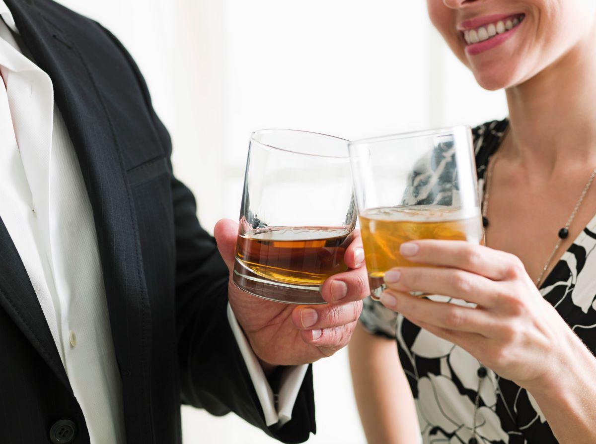 Man and woman holding glasses of whiskey