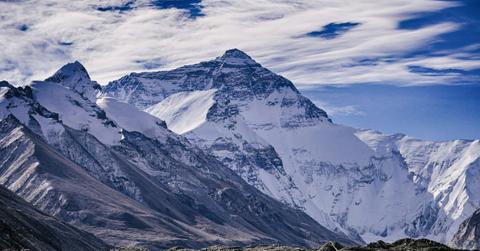 Mount Everest stands tall against the blue and white clouds in the background