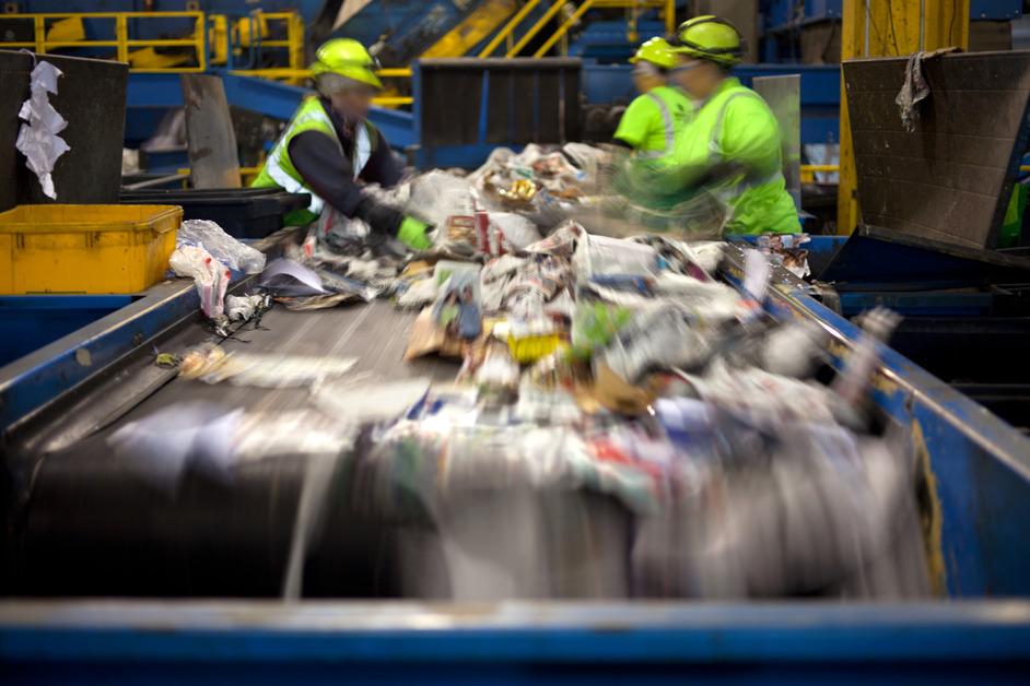 Stock photo of people sorting recycling and trash. 