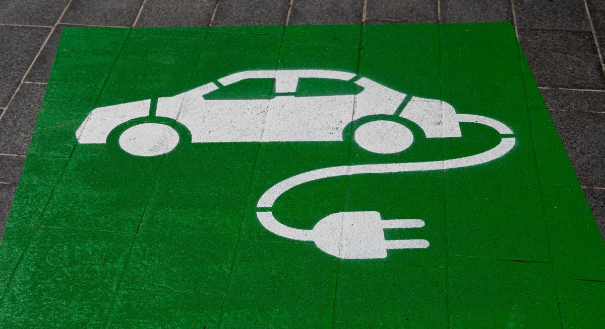 painted green and white EV charging sign on ground