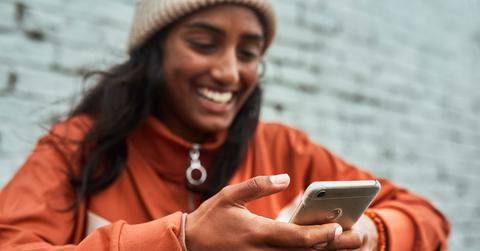 Gen Z girl laughing at her phone while sitting down.
