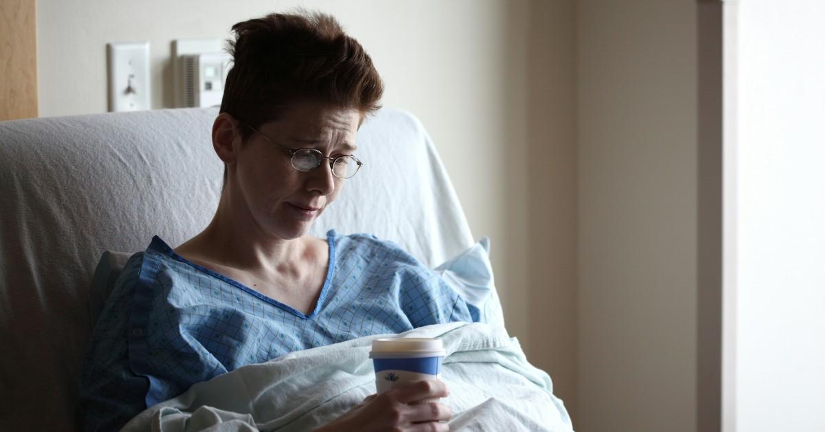 A sick woman sits in a hospital bed