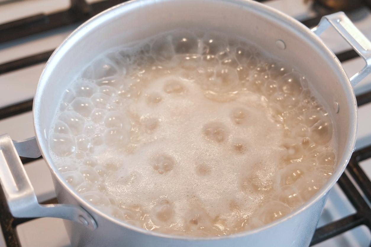 A pot of rice boiling on a stovetop.