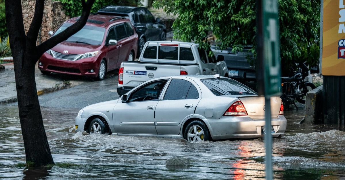 A silver car drives through flood waters