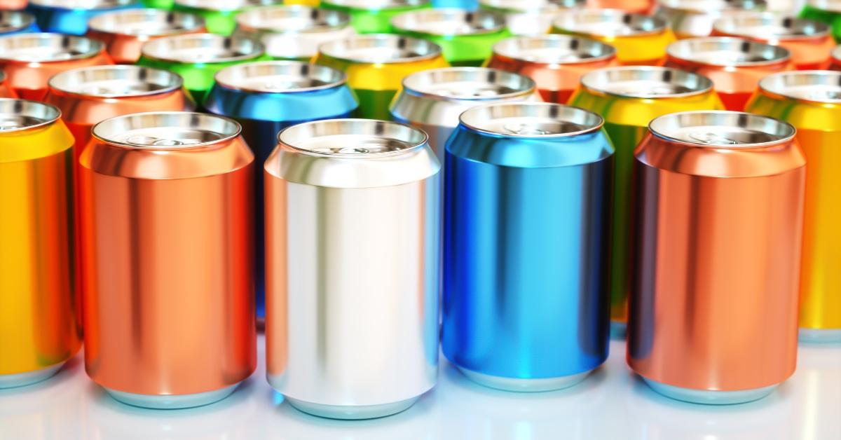 Orange, silver and blue cans of soda on a white countertop. 