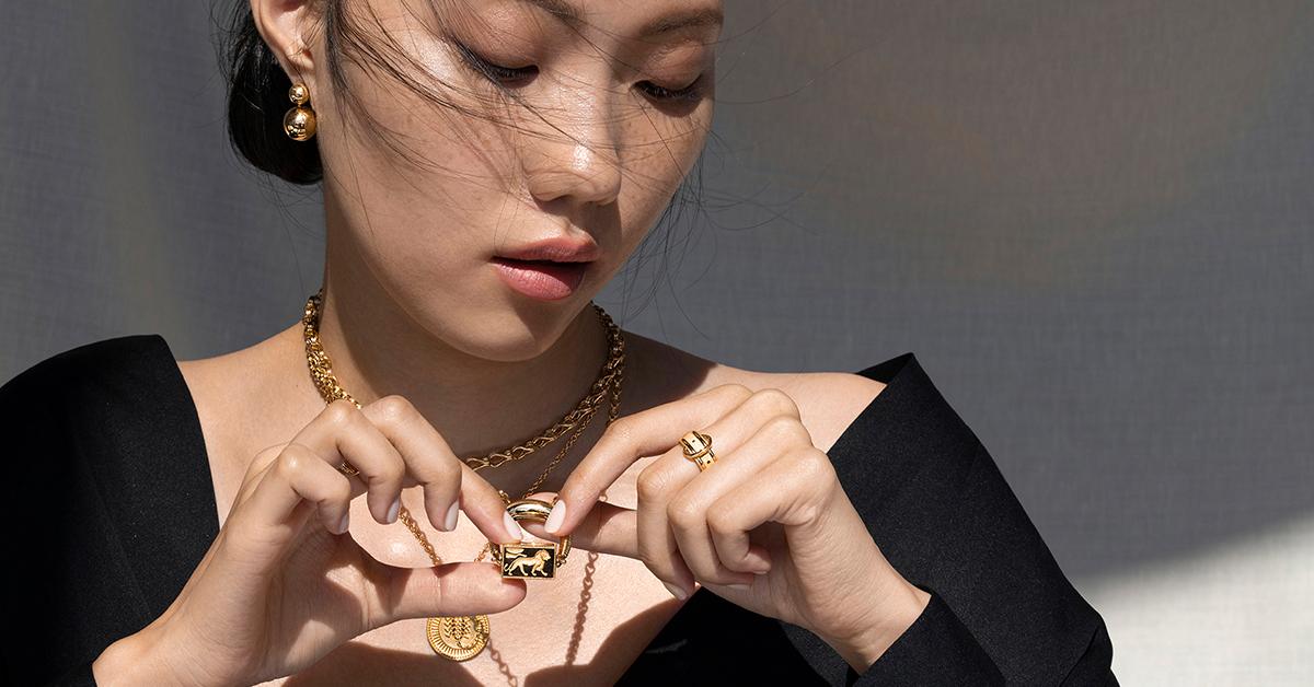 Model wears gold FUTURA Jewelry necklaces and ring