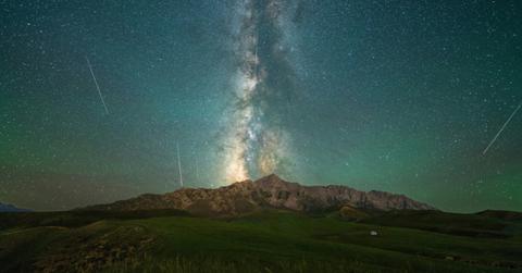 Meteors light up the night sky over a mountain range