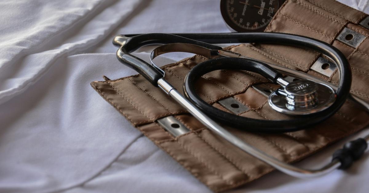 Doctor's stethoscope and kit in a brown bag on white hospital sheets. 