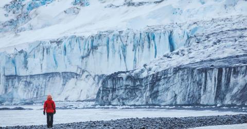 A man standing in front of a massive glacier. (Representative Cover Image Source: Getty Images | anyaberkut)