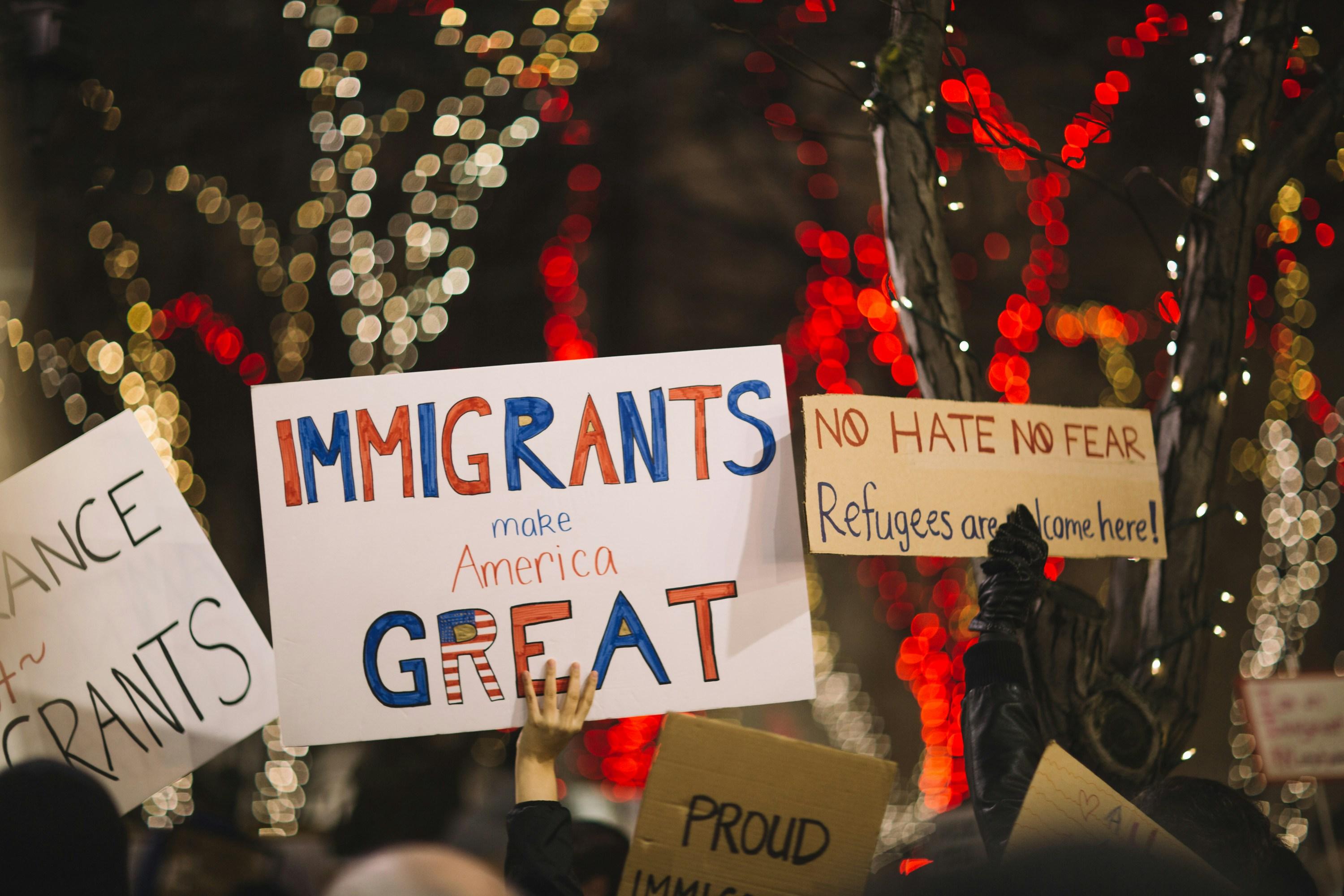 Immigrants hold up posters protesting the hatred against them.