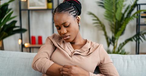 A woman scratching at her arm on the couch.