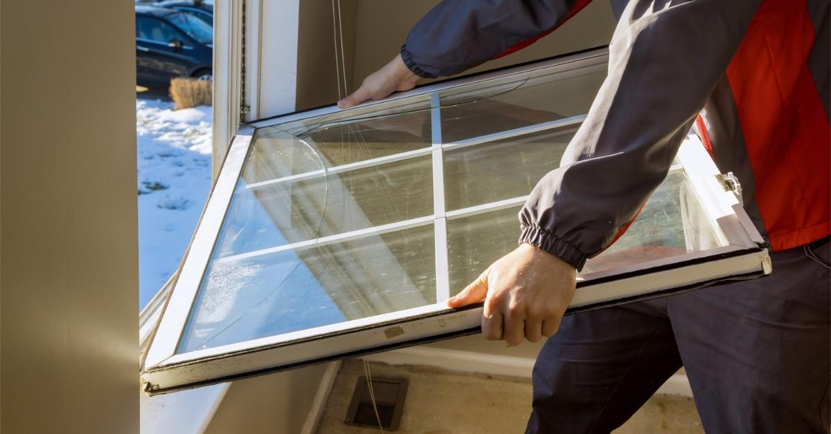 Man removes old broken window from frame