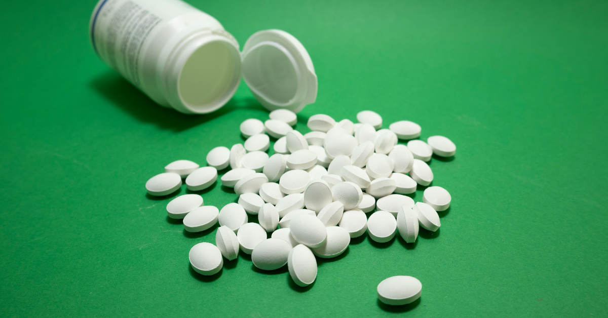 White pills spill out on a green background