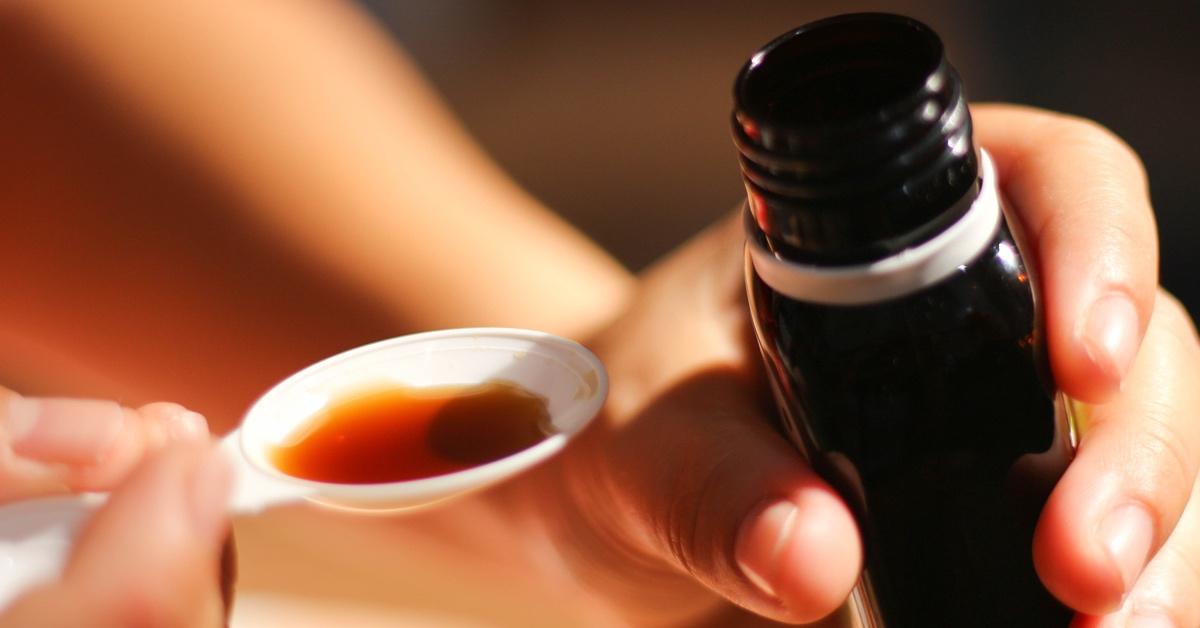 Person pouring cough syrup out into a spoon. 