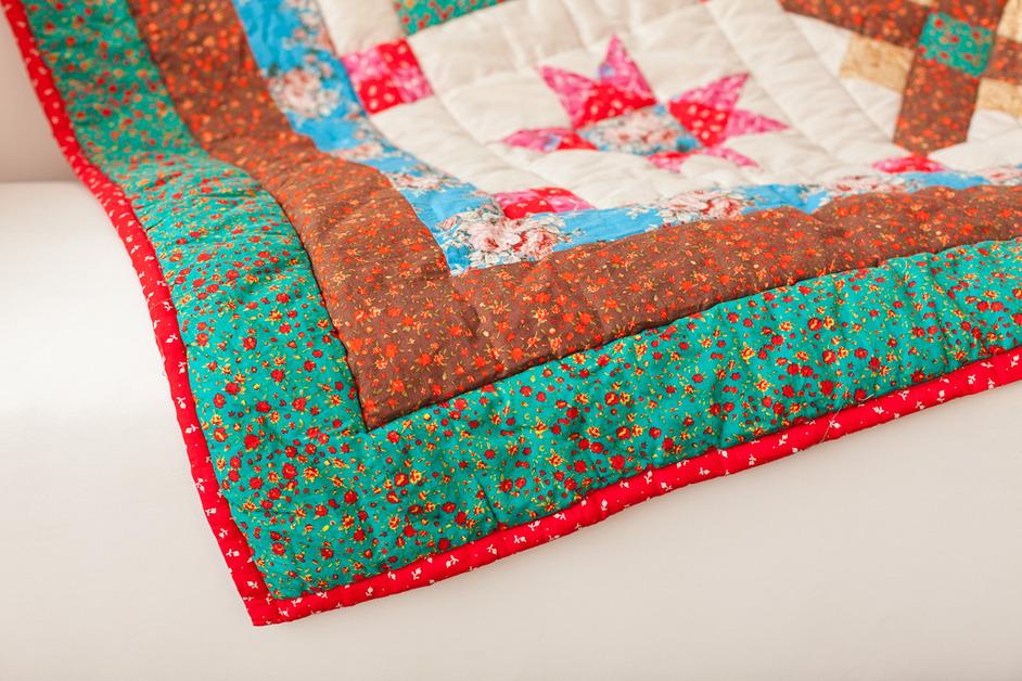 A colorful quilt sits on a white couch. 