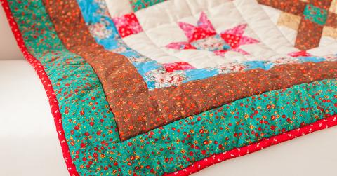 A colorful quilt sits on a white couch.