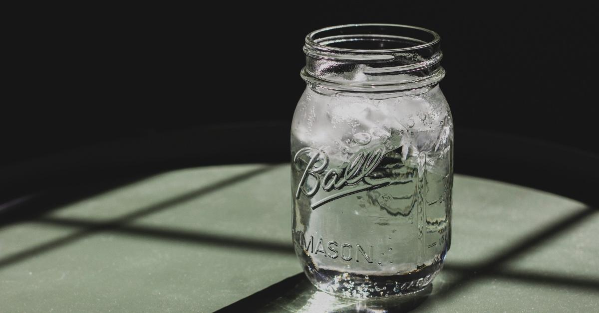 Glass of water in a Ball mason jar on a green background. 